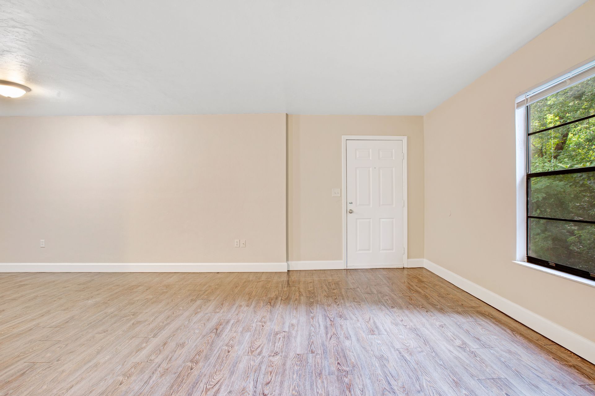 An empty living room with hardwood floors and a window.