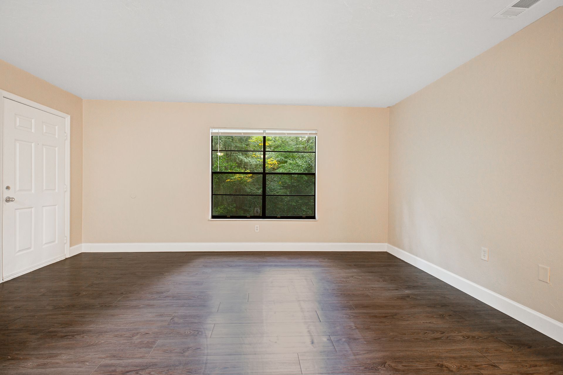 An empty living room with hardwood floors and a window.