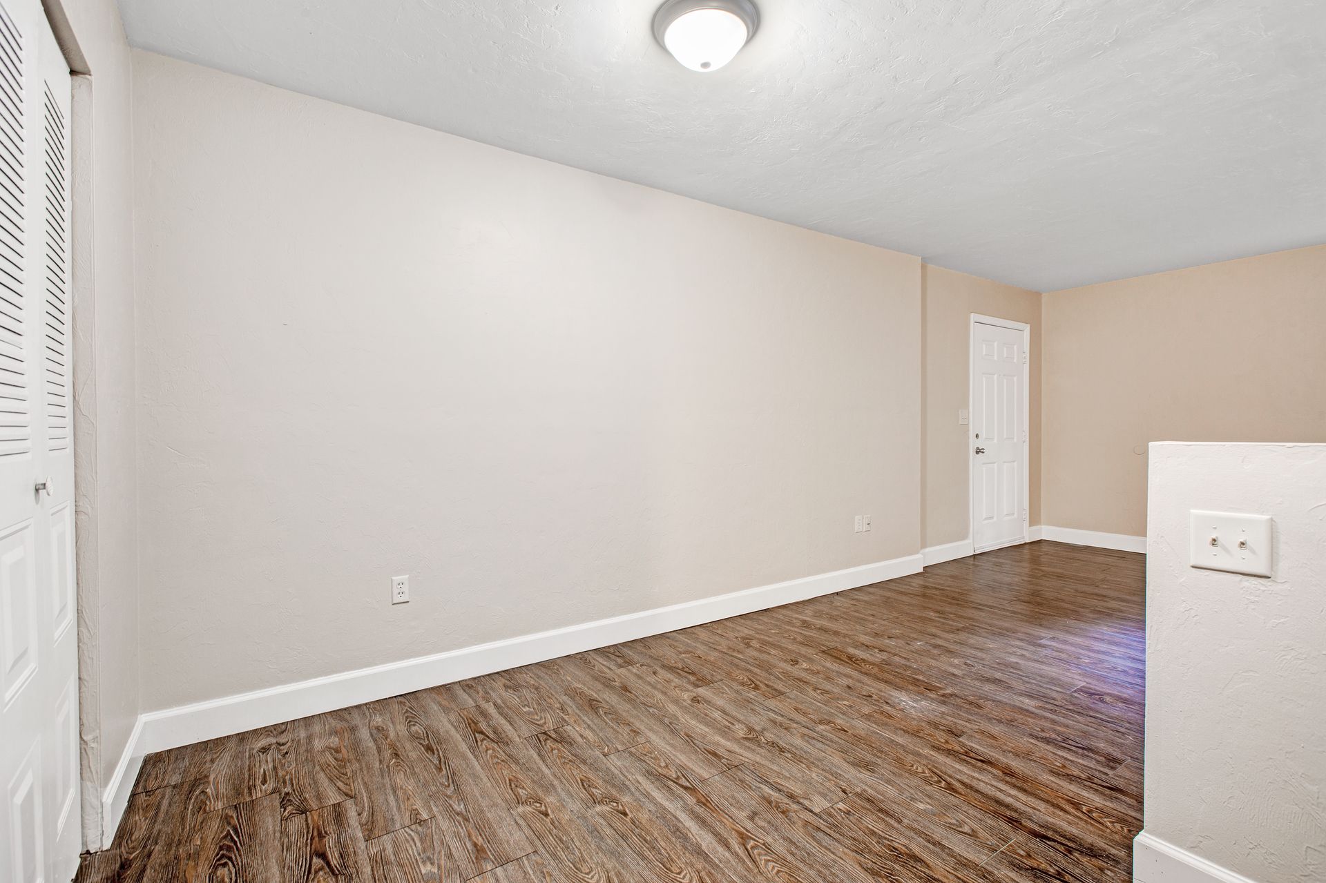 An empty room with hardwood floors and white walls.