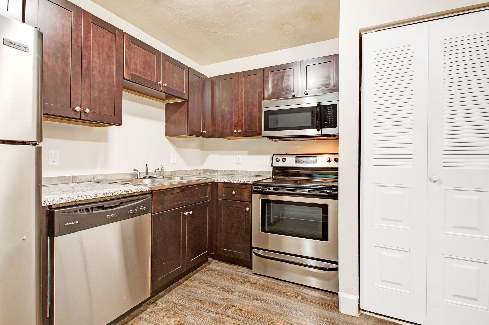 A kitchen with stainless steel appliances and brown cabinets.