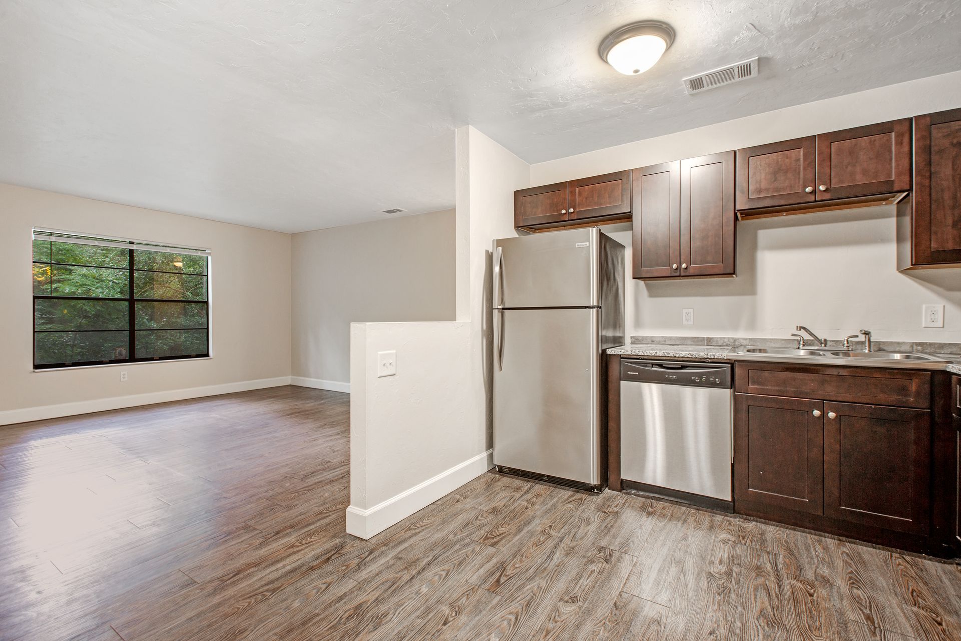 An empty kitchen with stainless steel appliances and wooden cabinets.