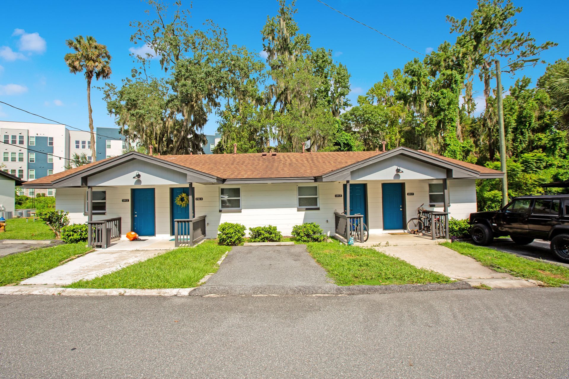 Two apartment buildings with blue doors are next to each other.