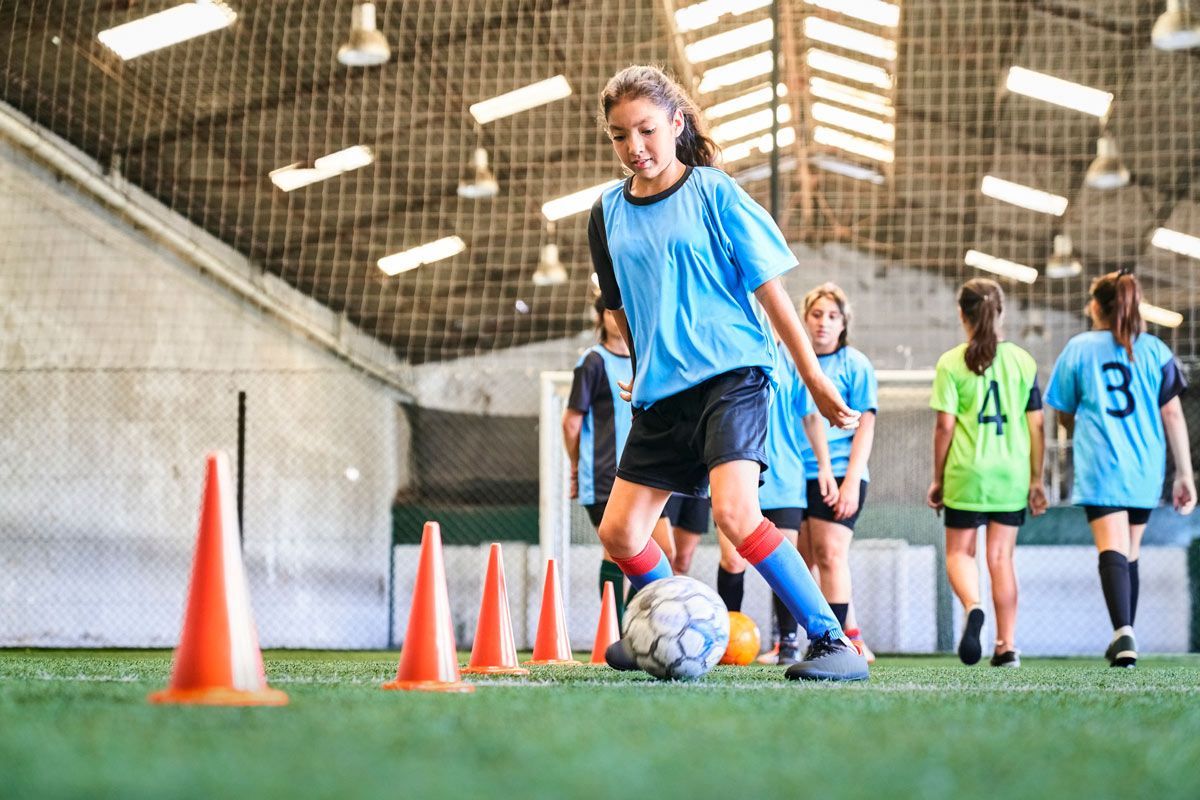 A group of young girls are playing soccer indoor