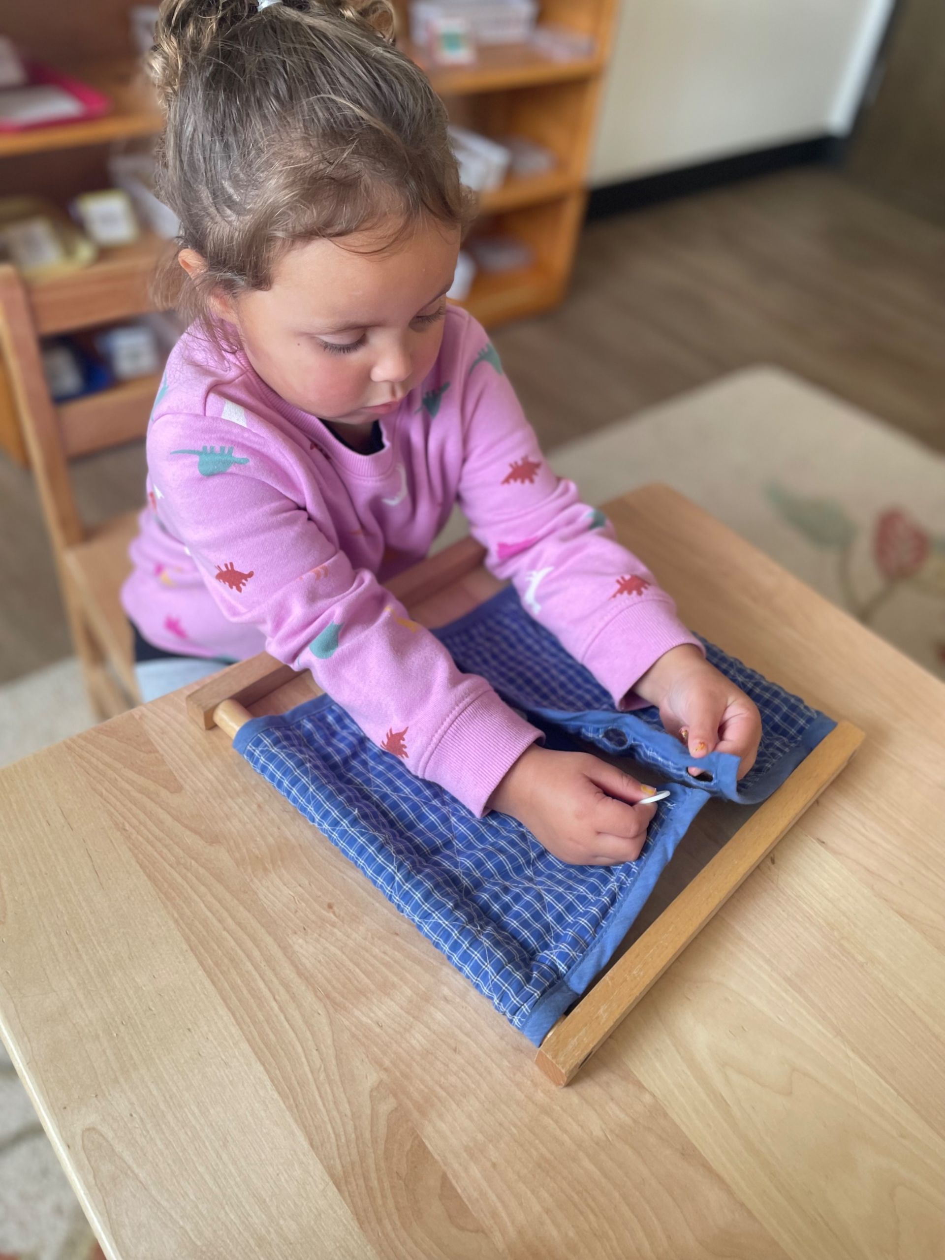 montessori child working with button frame
