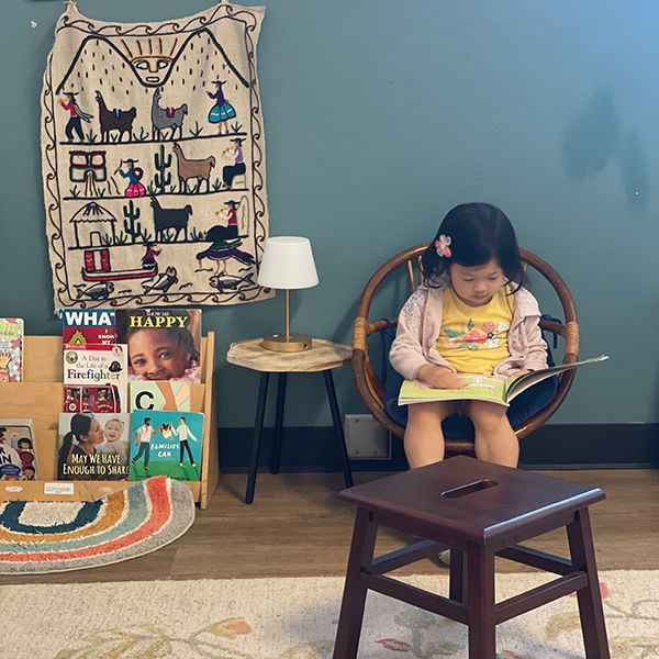 montessori child reading a book inside the classroom