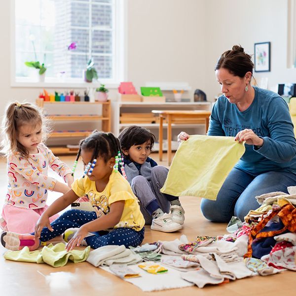 montessori guide and children folding clothes