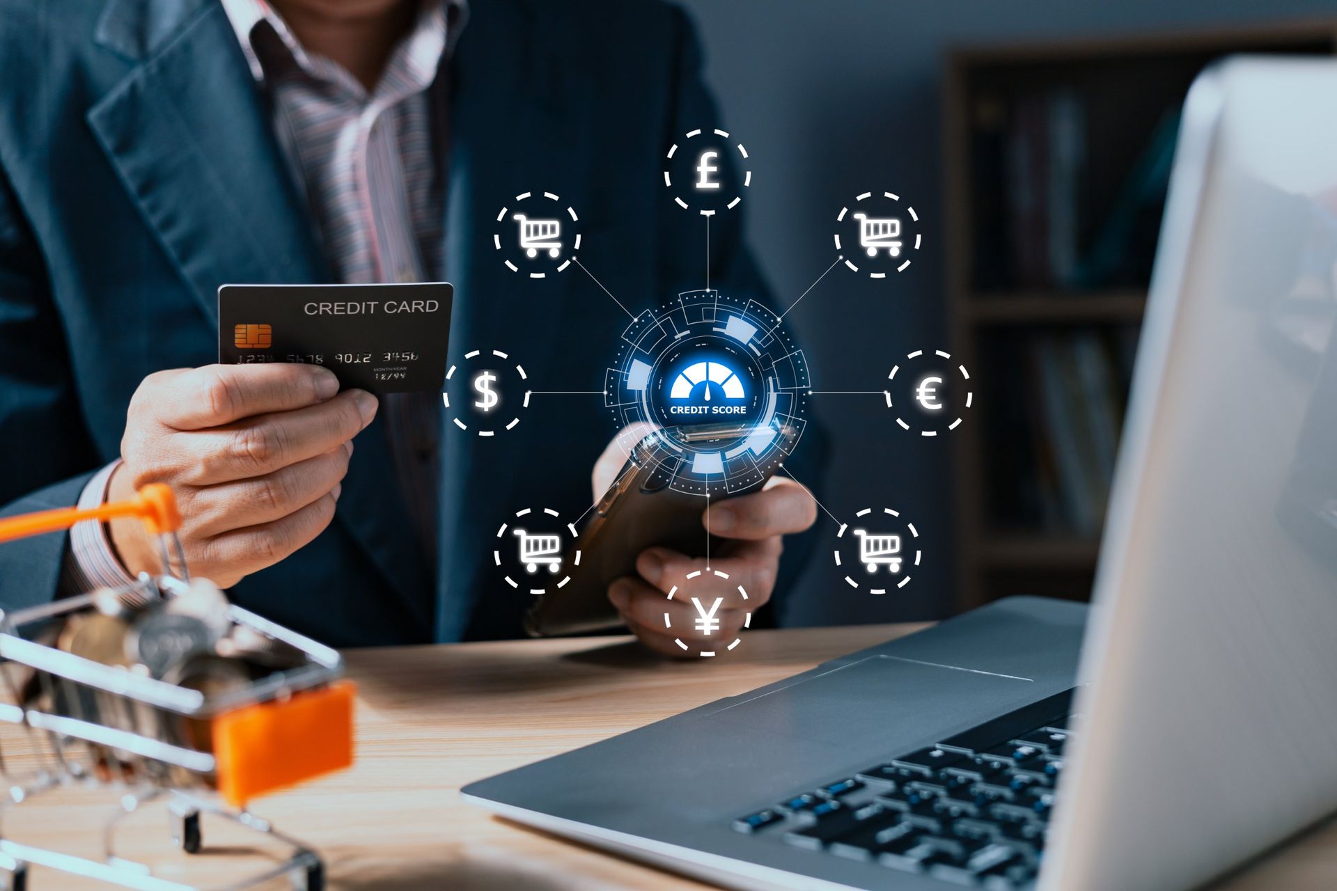 Person holding a credit card and phone, interacting with online shopping icons near a laptop and shopping cart.