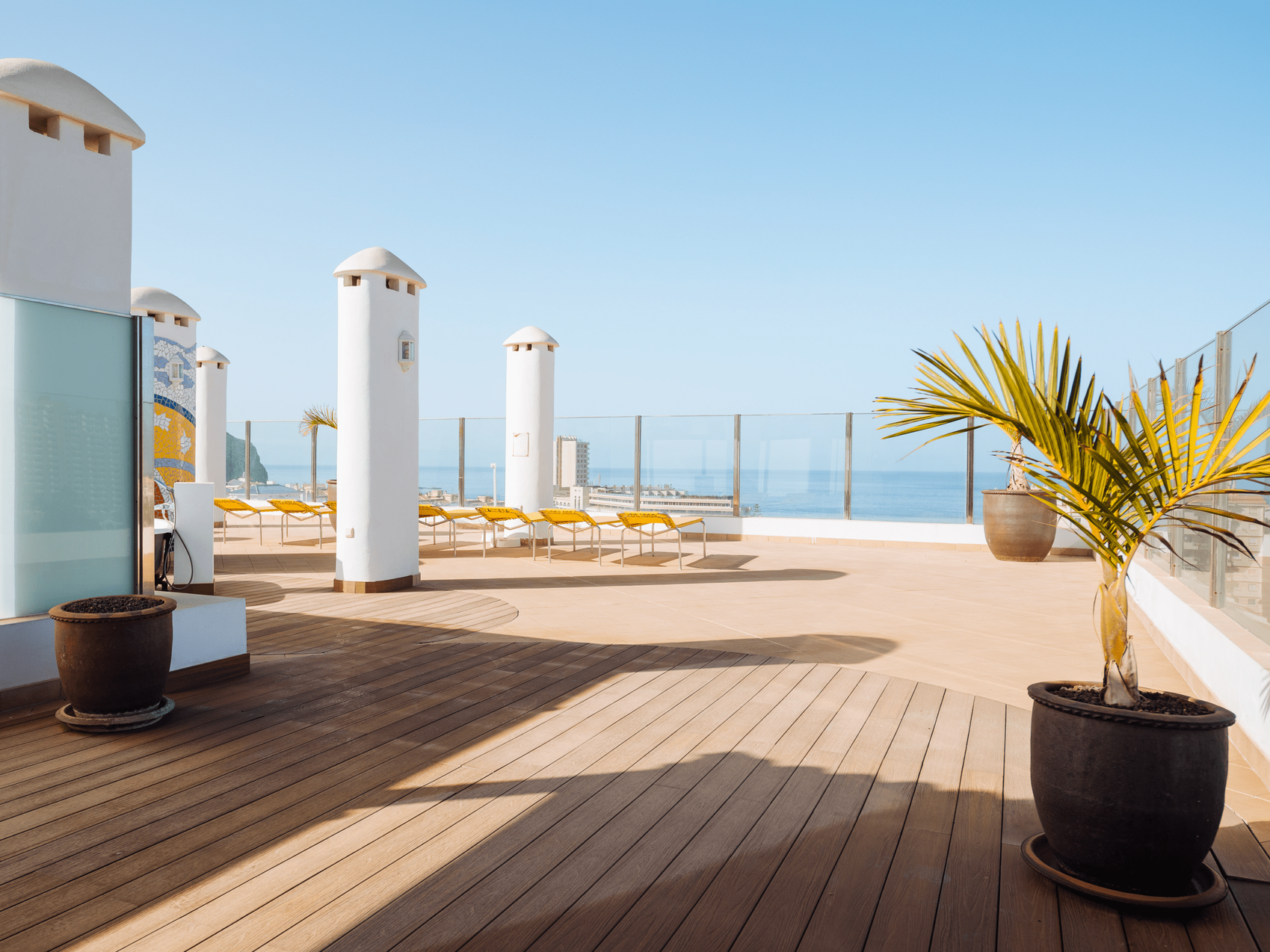 Eine Dachterrasse mit Blick auf das Meer und eine Palme.