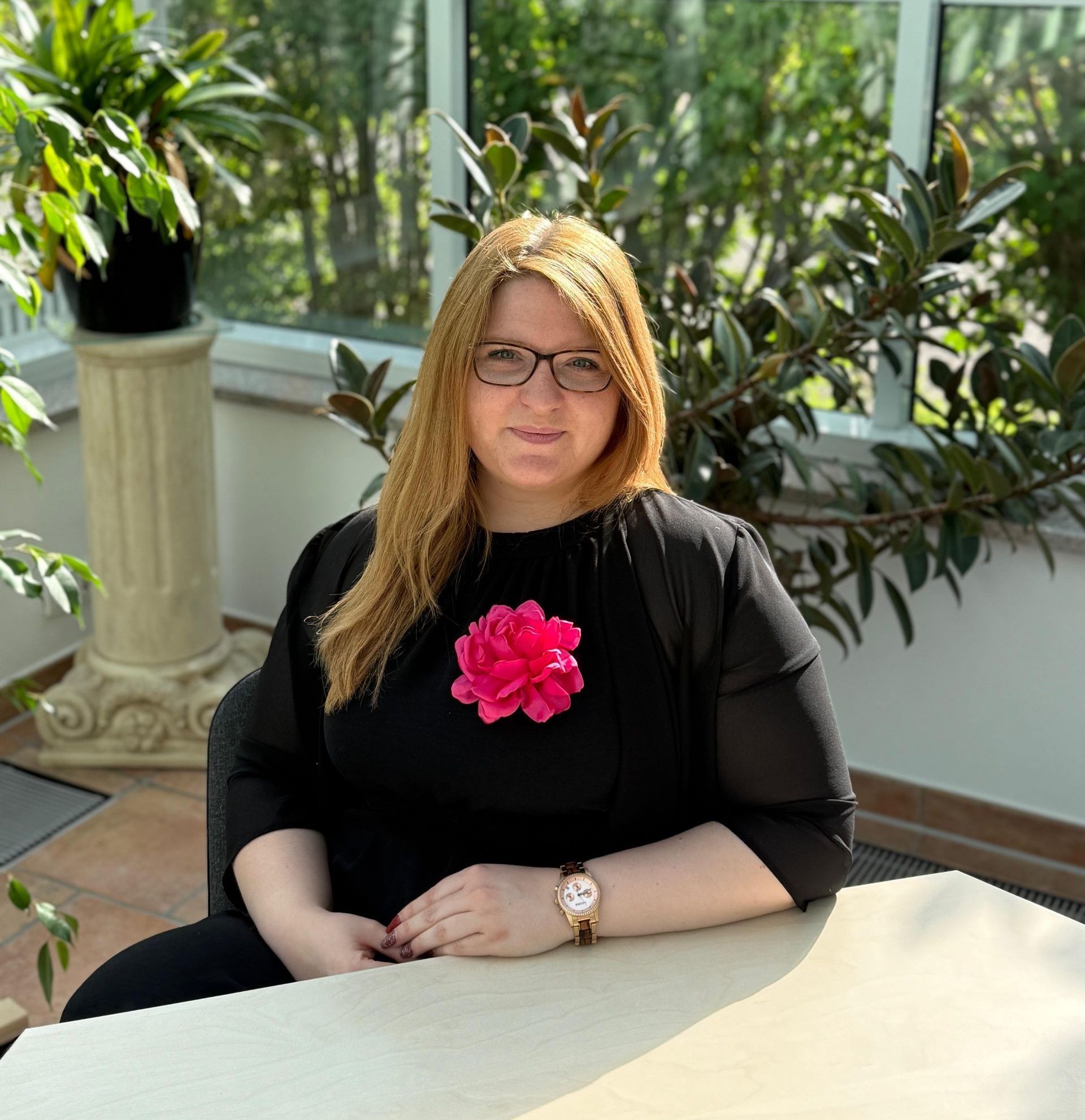 Eine Frau mit Brille und blauem Hemd steht in einem Feld aus lila Blumen.