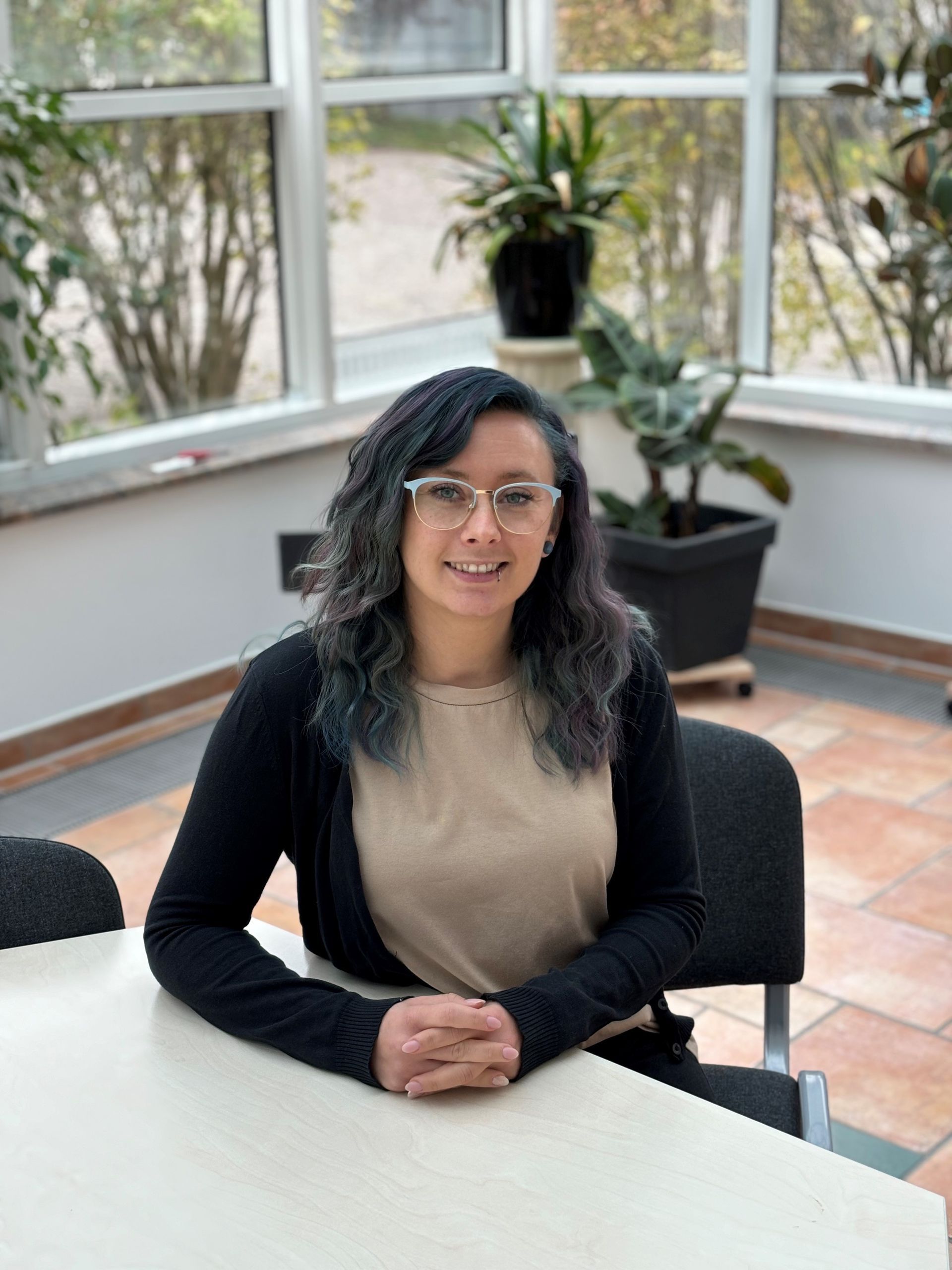 Eine Frau mit lila Haaren trägt eine Brille und einen lila Pullover