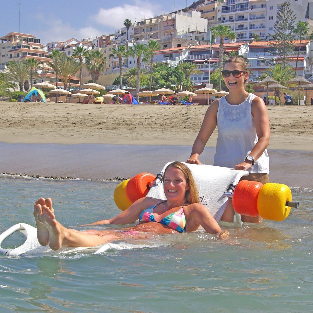 Eine Frau wird mit einem Strand-Buggy ins Meer geschoben.