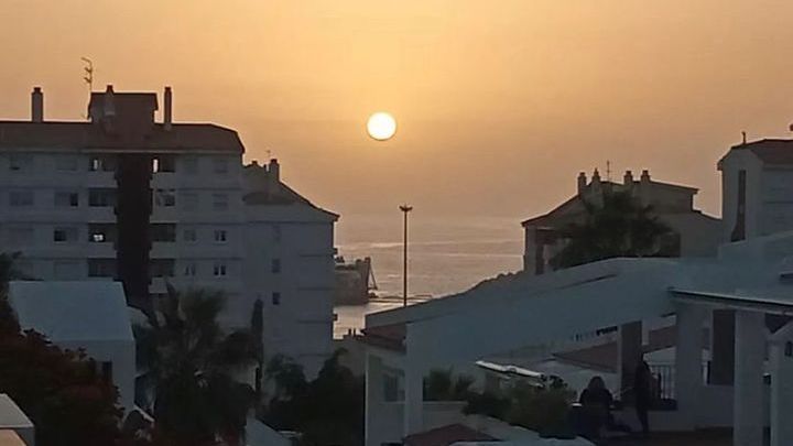 Die Sonne geht über dem Meer und den Gebäuden im Vordergrund unter.