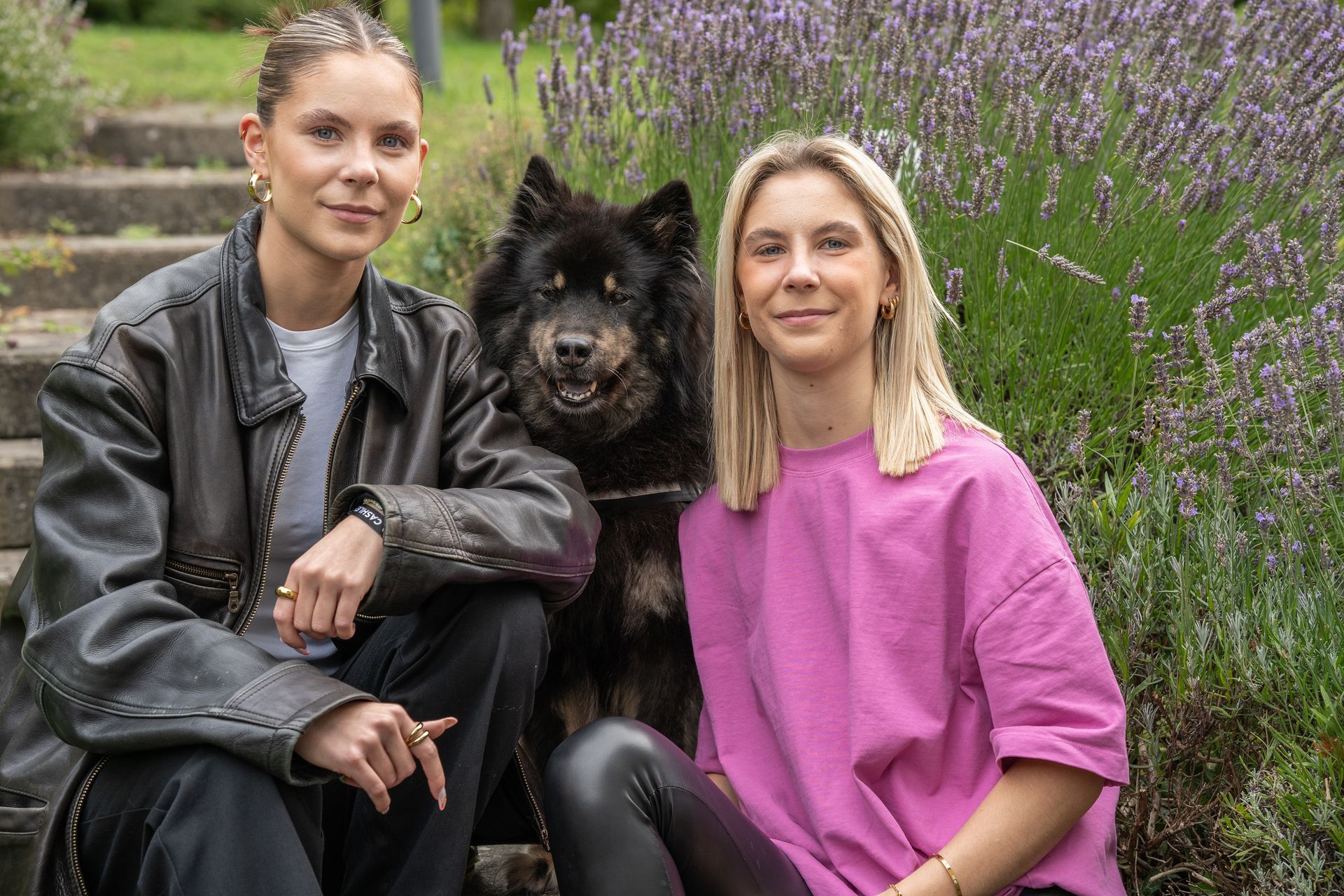 Zwei Frauen sitzen mit einem Hund nebeneinander.