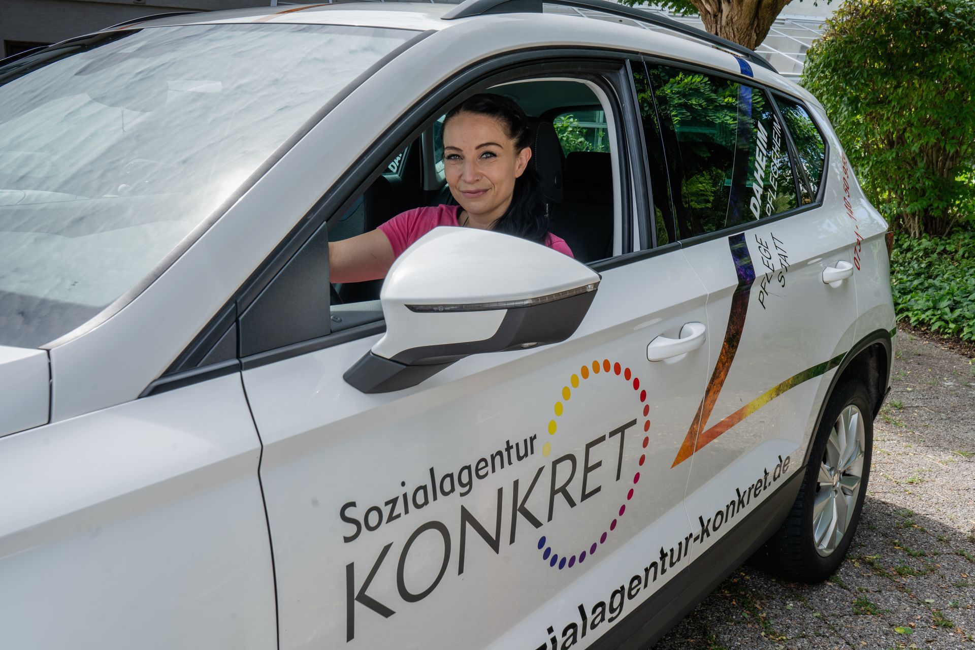 Eine Frau sitzt auf dem Fahrersitz eines weißen Autos.