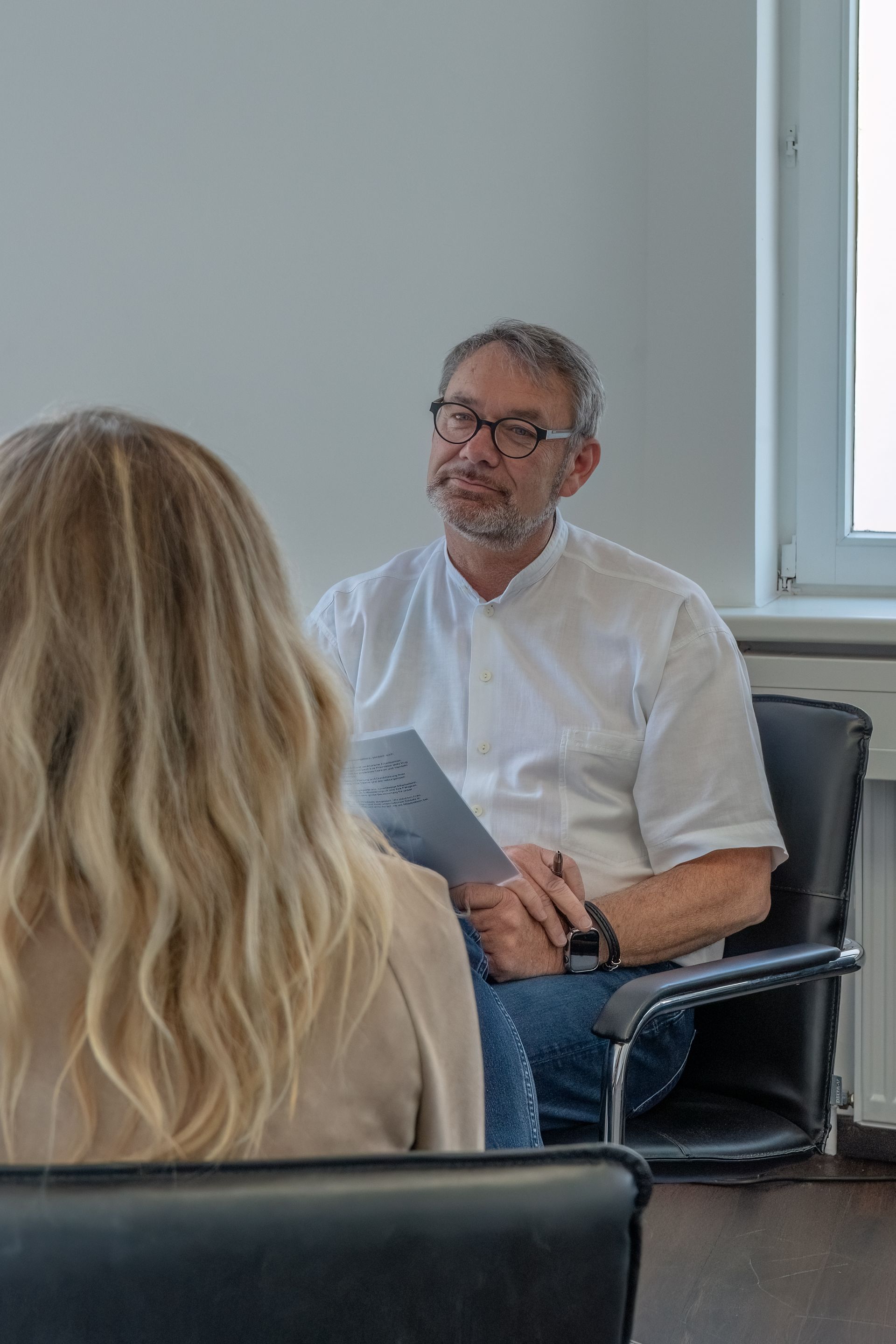 Ein Mann sitzt auf einem Stuhl und spricht mit einer Frau.