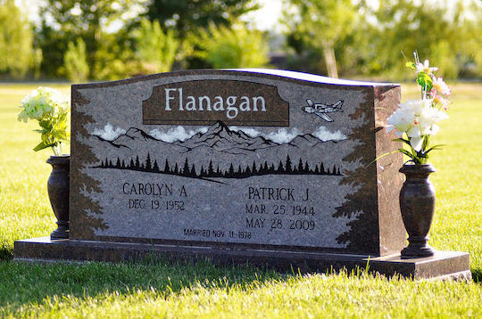 Gravestone for the Flanagan family with mountain landscape. Carolyn A. Dec 1952. Patrick J. Mar 25 1954 - May 24 2009.