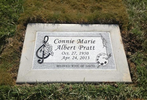 Headstone of Connie Marie Albert Pratt, born Oct. 27, 1950, died Apr. 24, 2013, with musical and art-related symbols.