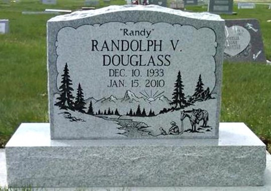 Gravestone of Randolph V. Douglass.  Gray stone features a mountain and forest scene. Dates: Dec 10, 1933 - Jan 15, 2010.