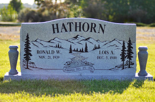 Gray headstone with the name HATHORN; names, dates, mountains, and trees.