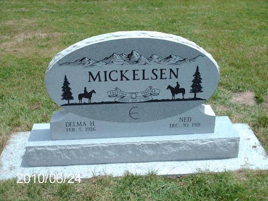 Gray granite headstone for Mickelsen family with mountain scene and horse riders.