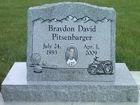 Gray headstone with a name, dates, photo, basketball, ATV, and mountain design.