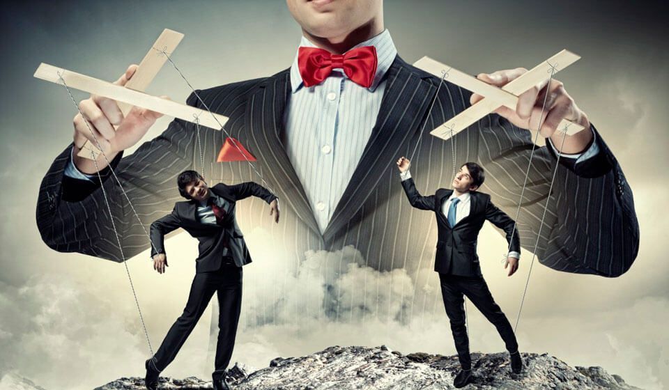 Puppeteer controlling two suited figures with strings; metaphor for manipulation.