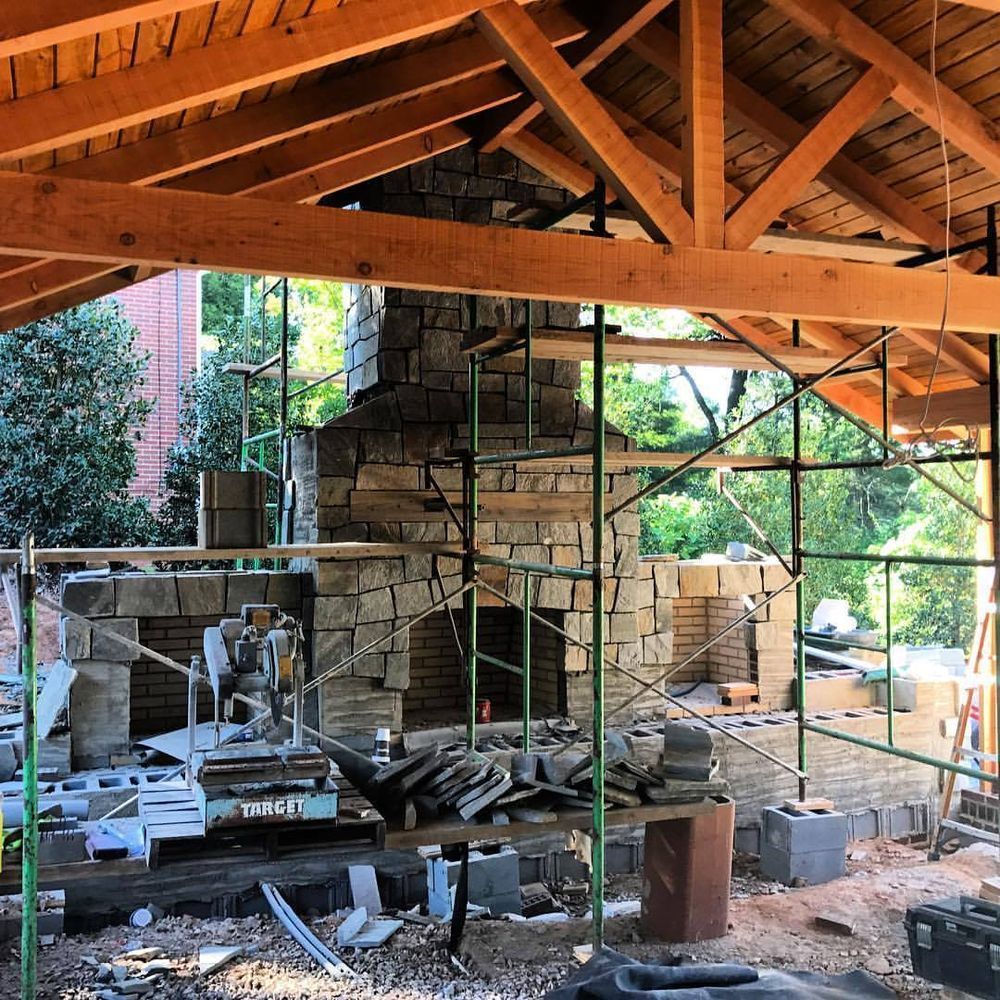 Scaffolding around a stone fireplace under a wooden roof in a construction site