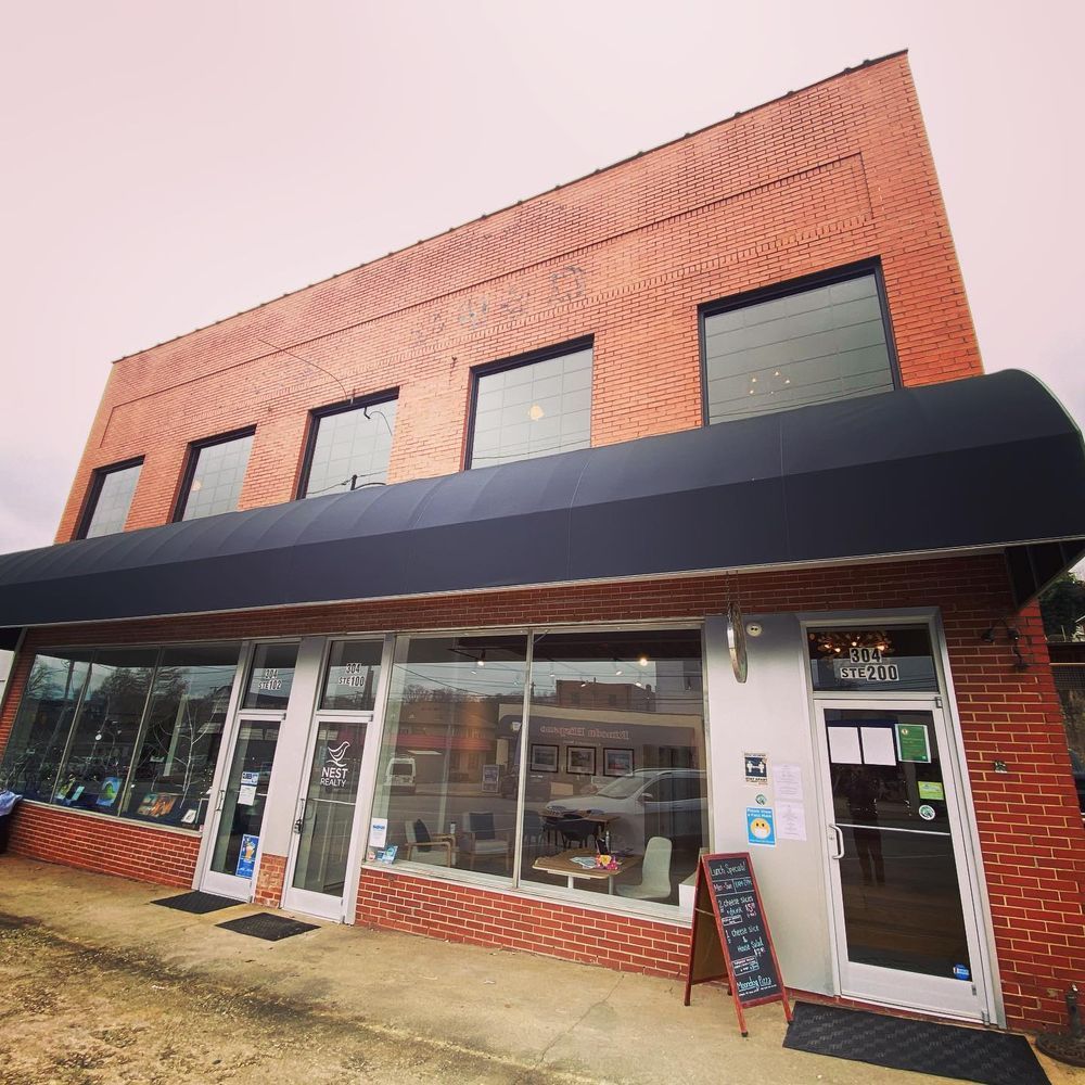 Brick storefront with black awning and large windows on a street corner
