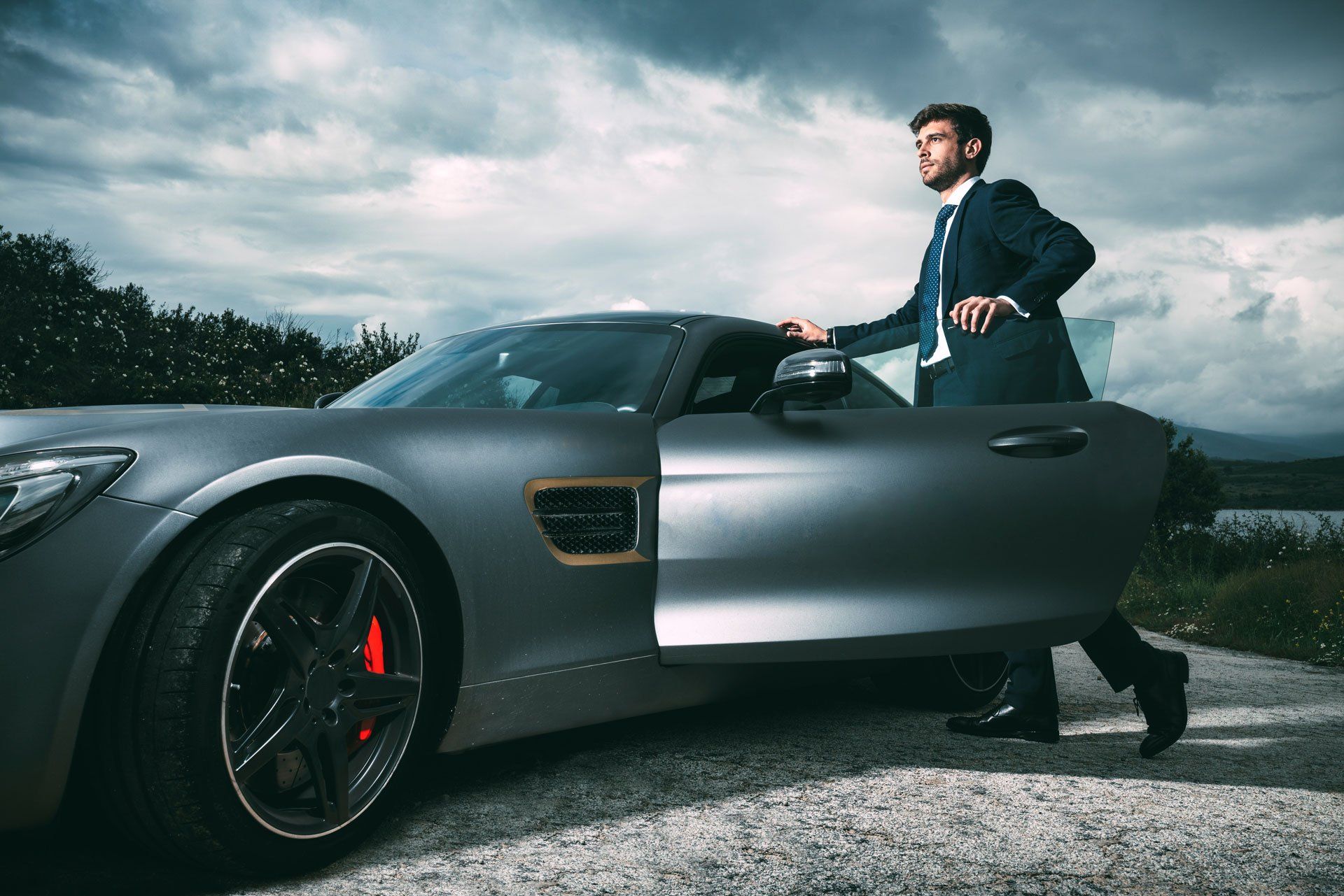 man standing near a luxury car