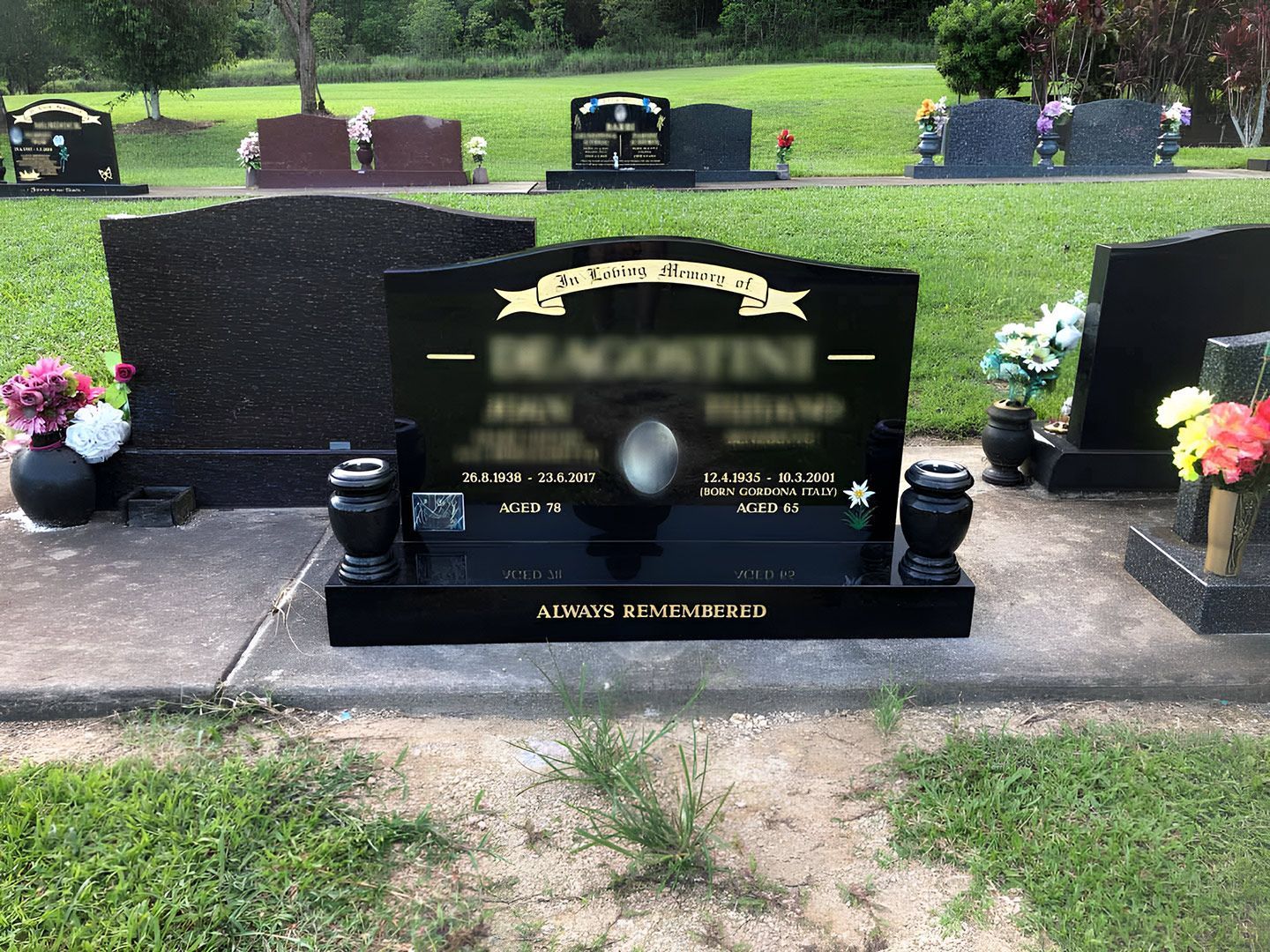 Black Headstone With Floral Arrangements in a Cemetery — Gori Marble & Granite Pty Ltd in Earlville, QLD