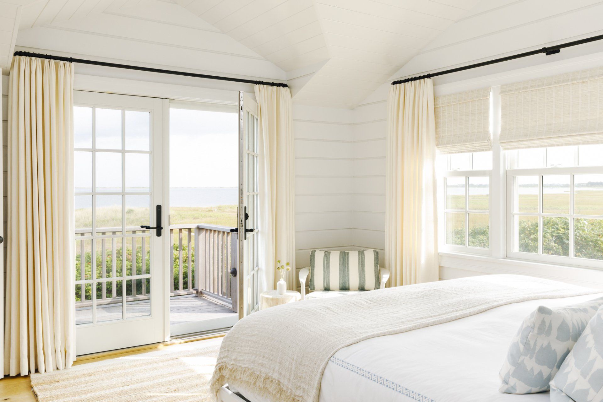 A bedroom with a bed and a balcony with a view of the ocean.