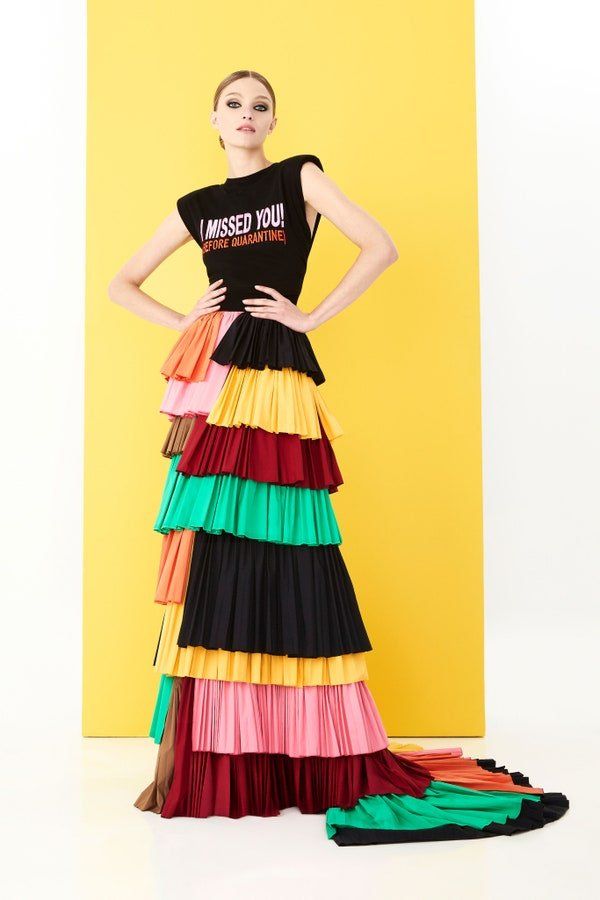 A woman is wearing a black t-shirt and a long colorful skirt