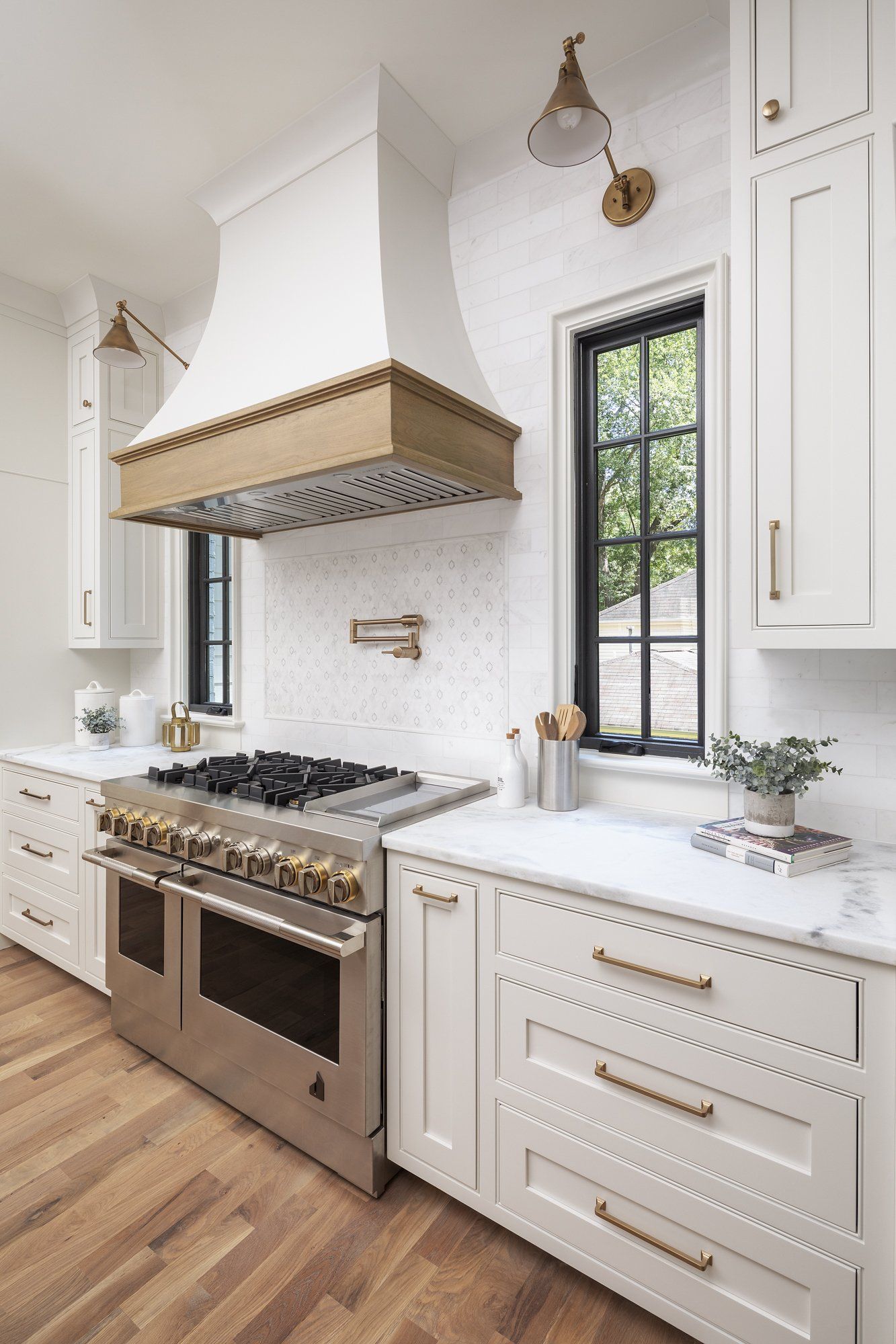 A kitchen with white cabinets , stainless steel appliances , a stove and a window.