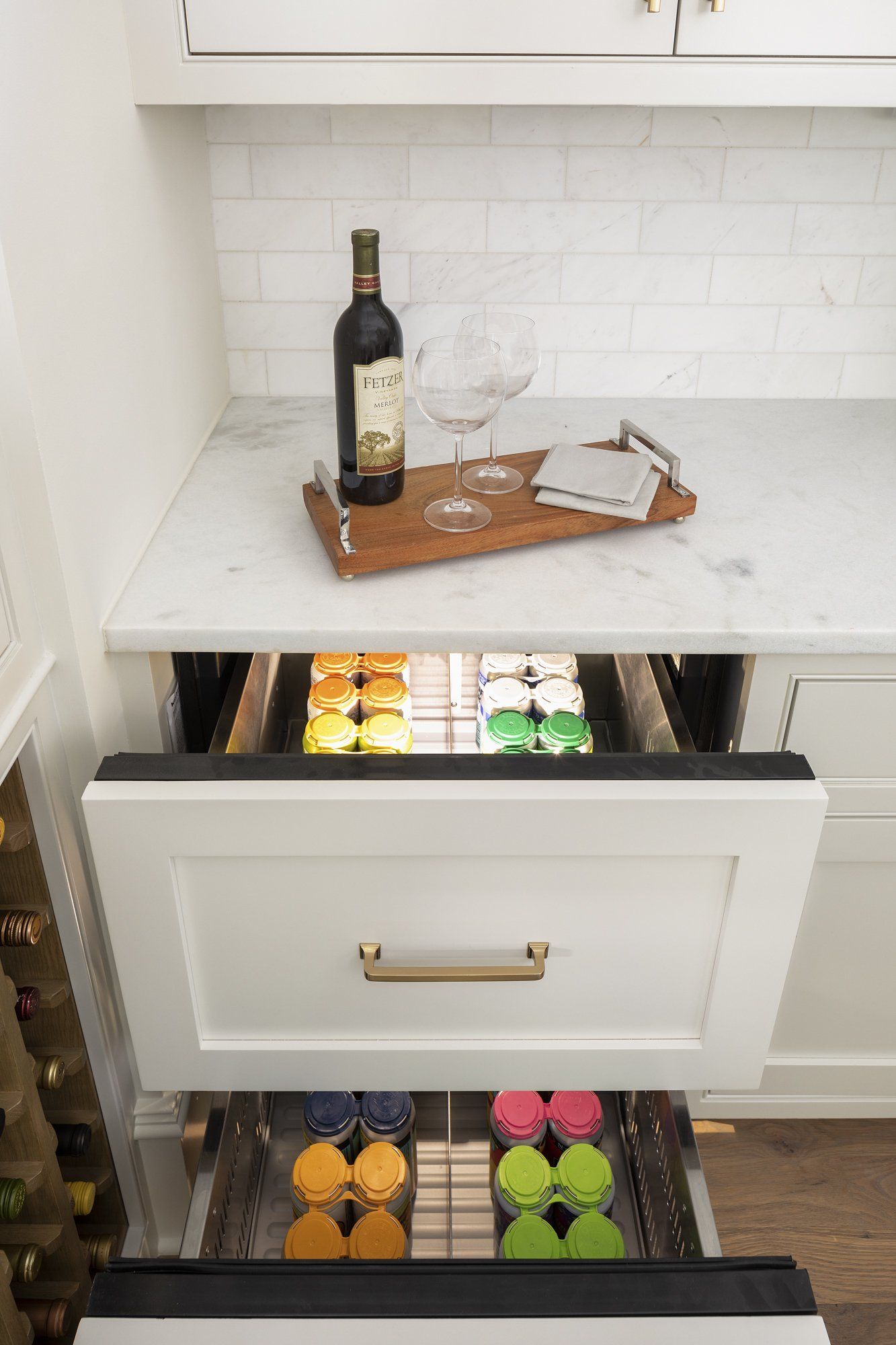 A bottle of wine is sitting on top of a tray in a kitchen drawer.