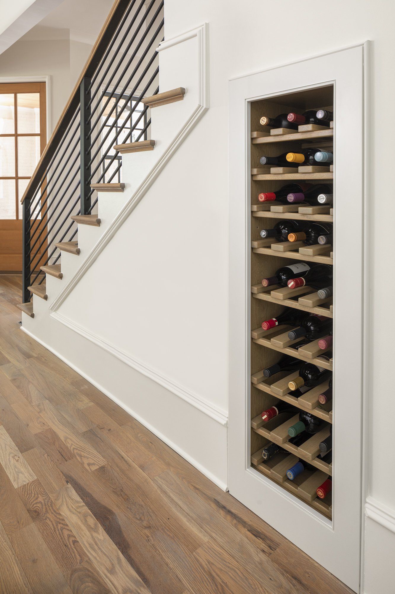 A wine rack is built into the wall next to a staircase.