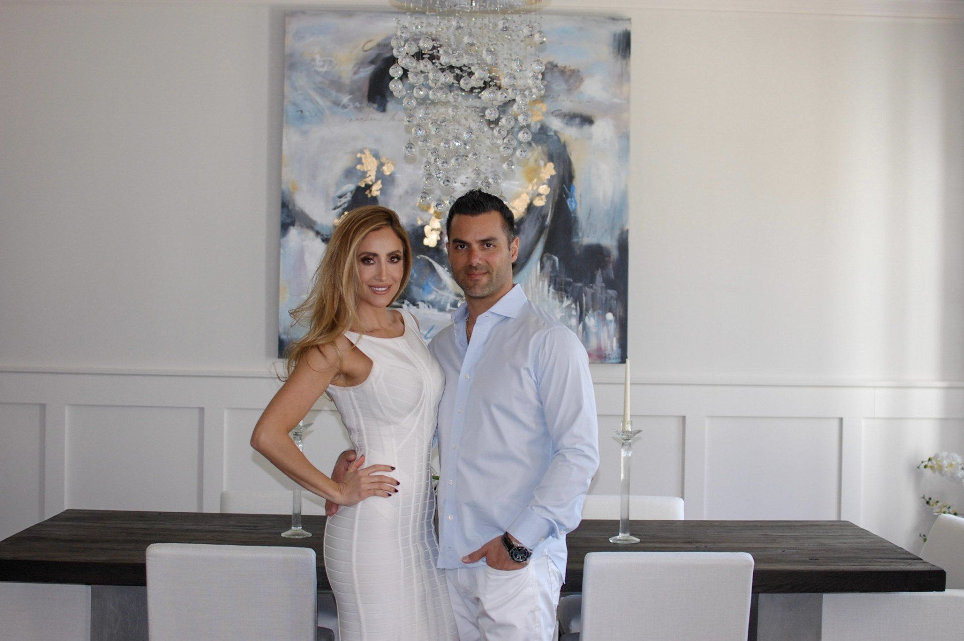 A man and a woman are posing for a picture in a dining room.