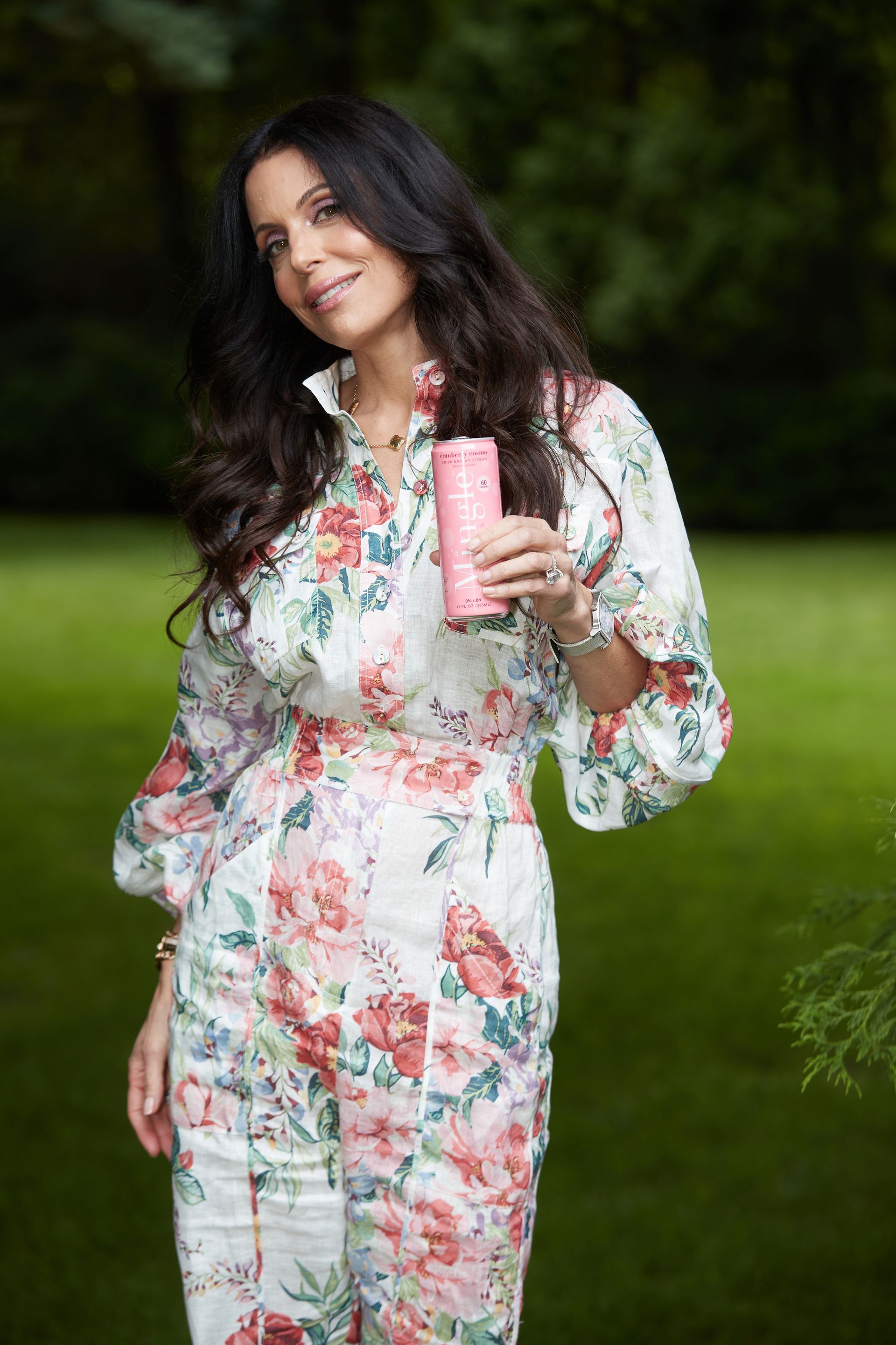 A woman in a floral jumpsuit is holding a can of soda.