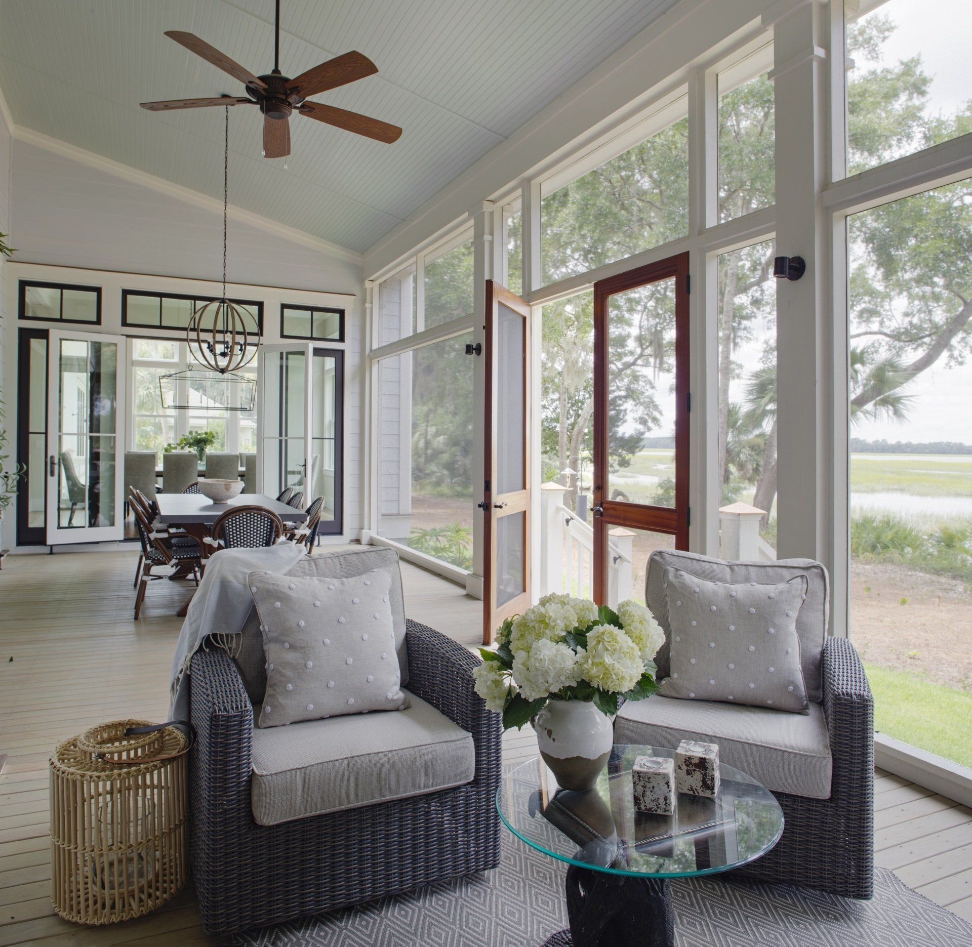 A living room with two chairs a table and a ceiling fan