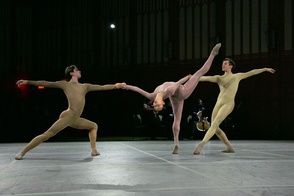 A group of three dancers are performing on a stage