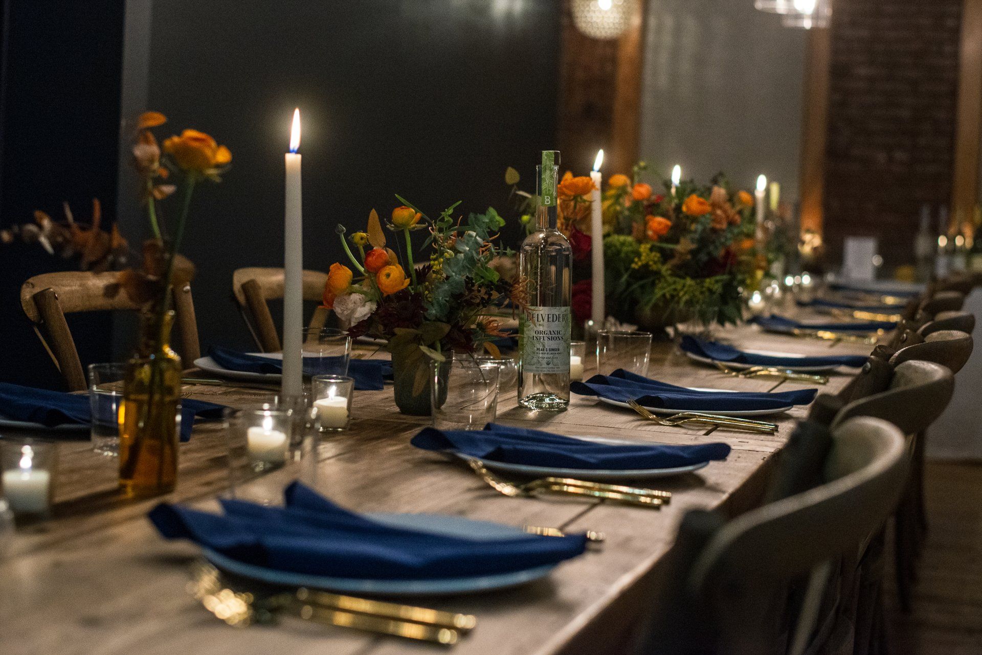 A long table with plates , napkins , candles and flowers on it.