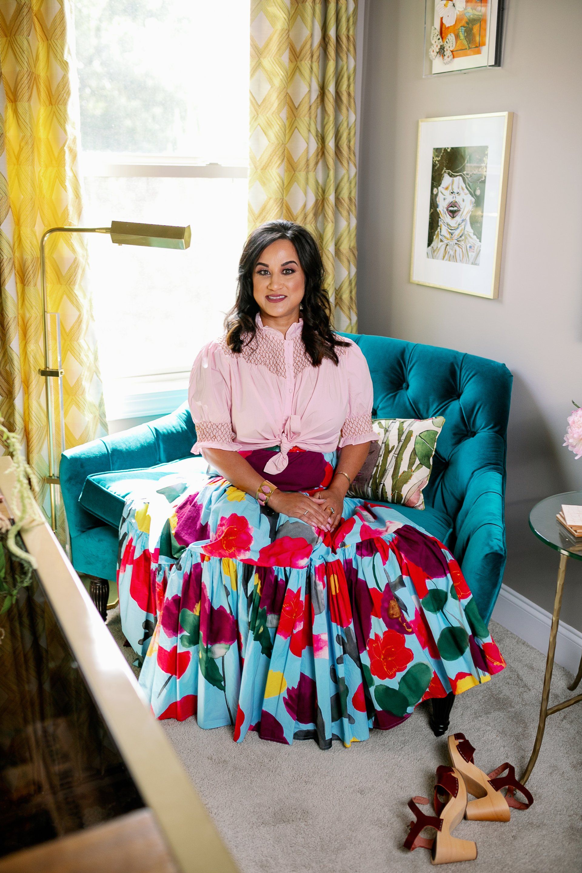 A woman is sitting in a chair wearing a floral skirt.