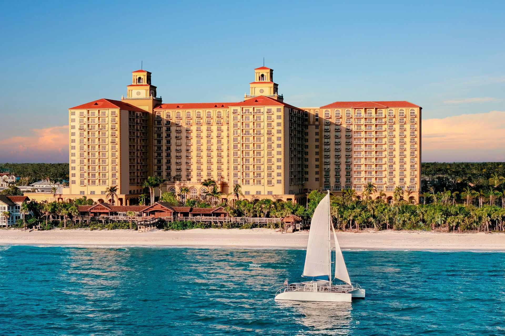 A sailboat is floating in the ocean in front of a large building.