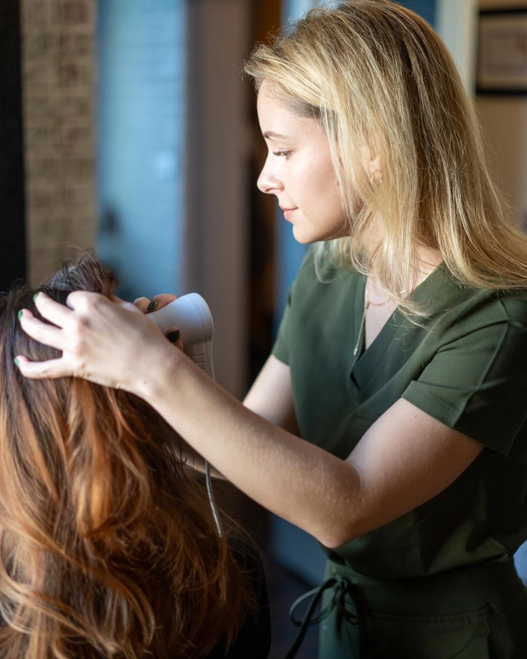 A woman is blow drying a woman 's hair in a salon.