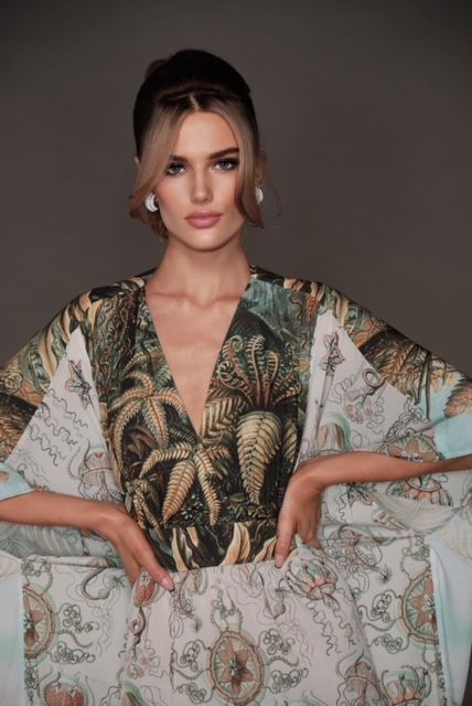 A woman is wearing a dress with a tropical print and a plunging neckline.