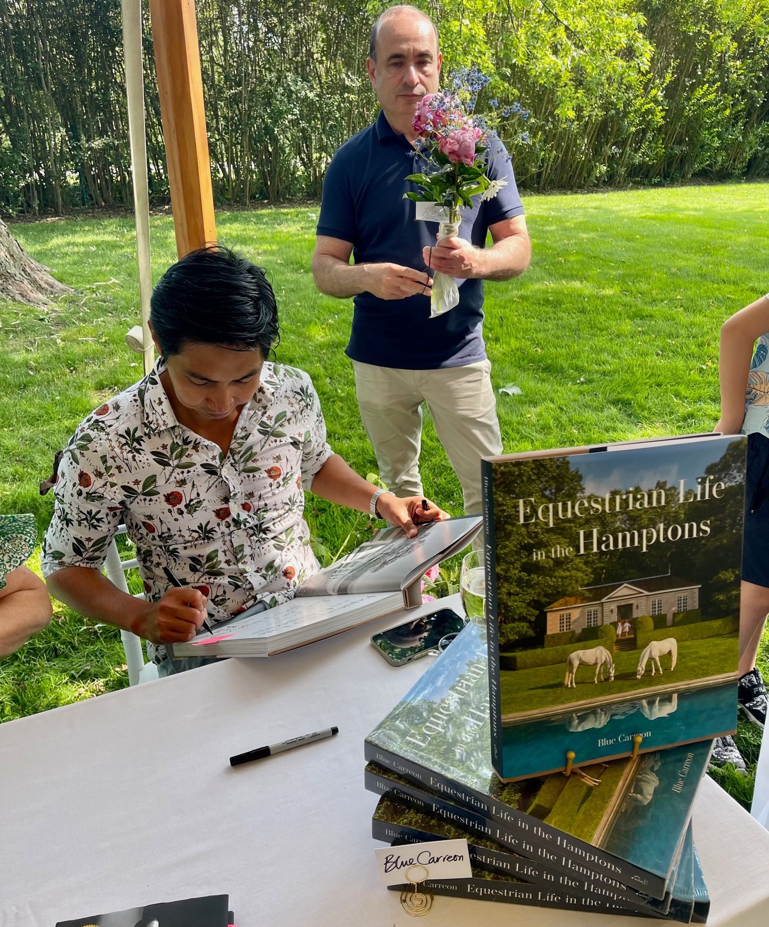 A man is sitting at a table signing a book.