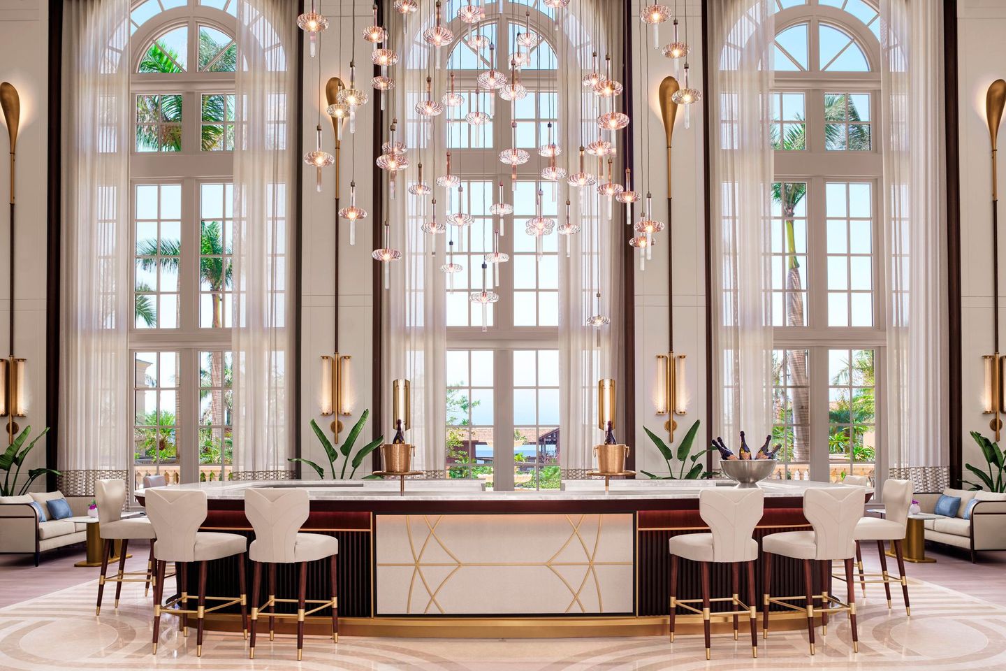 A large room with a bar , chairs , and a chandelier.