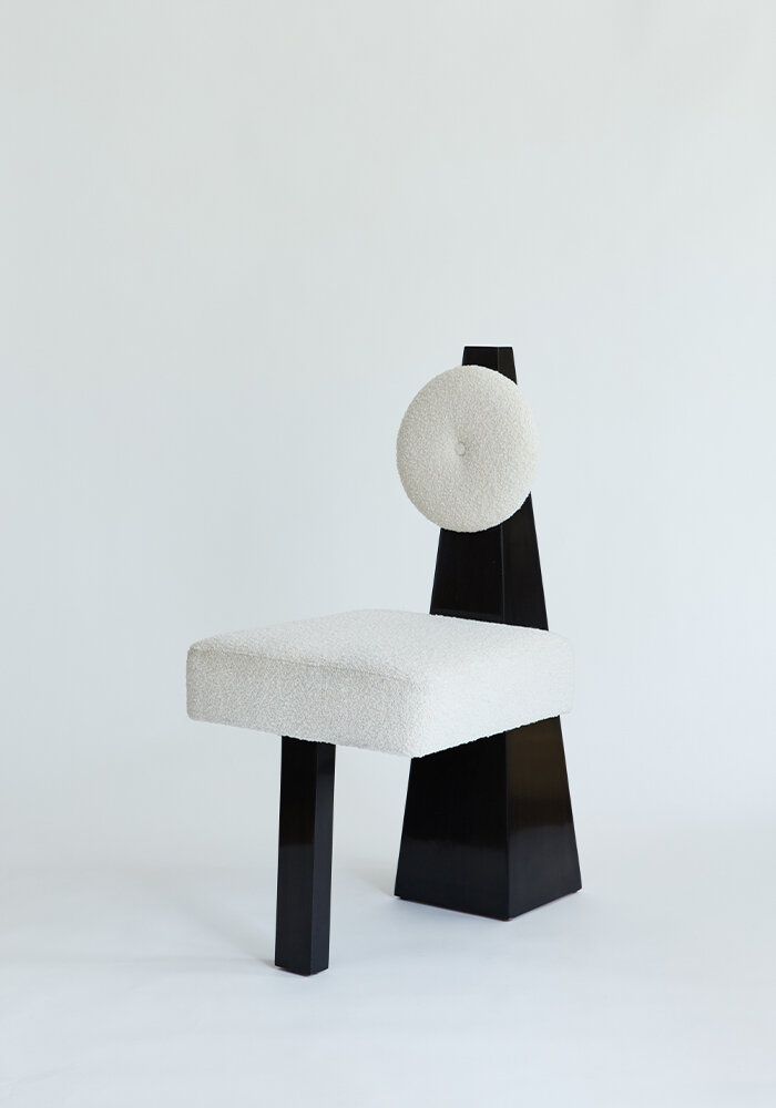 A black and white chair with a white cushion on the back is sitting on a white surface.