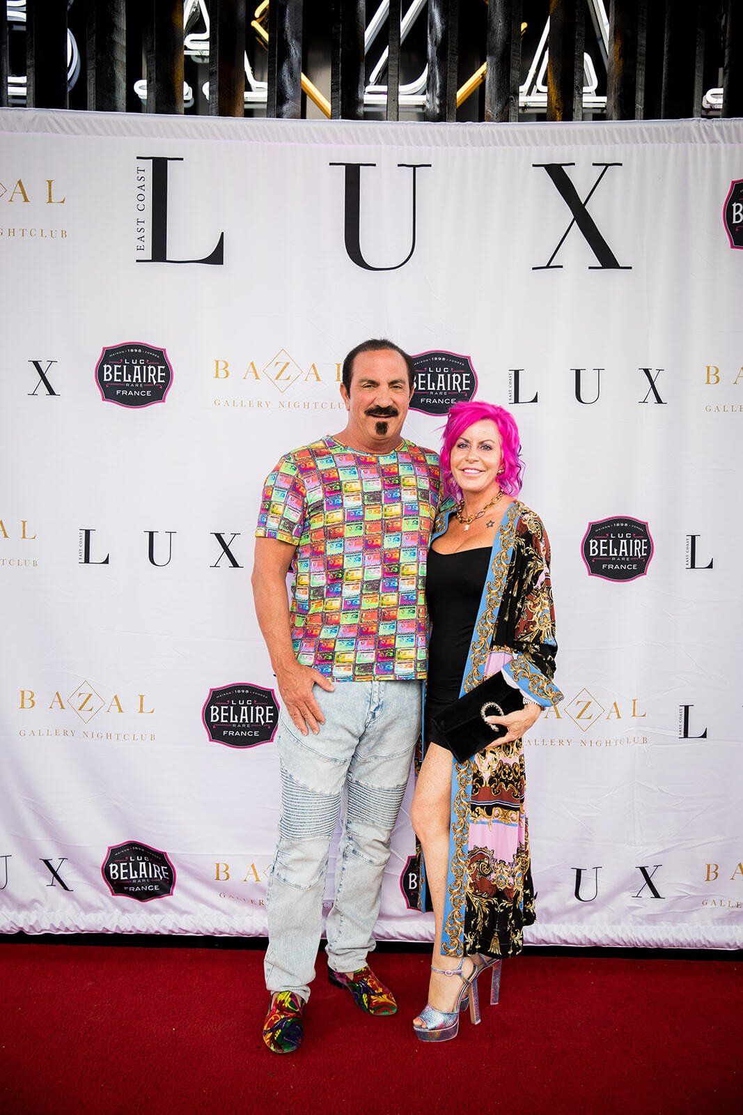 A man and a woman are posing for a picture on a red carpet.