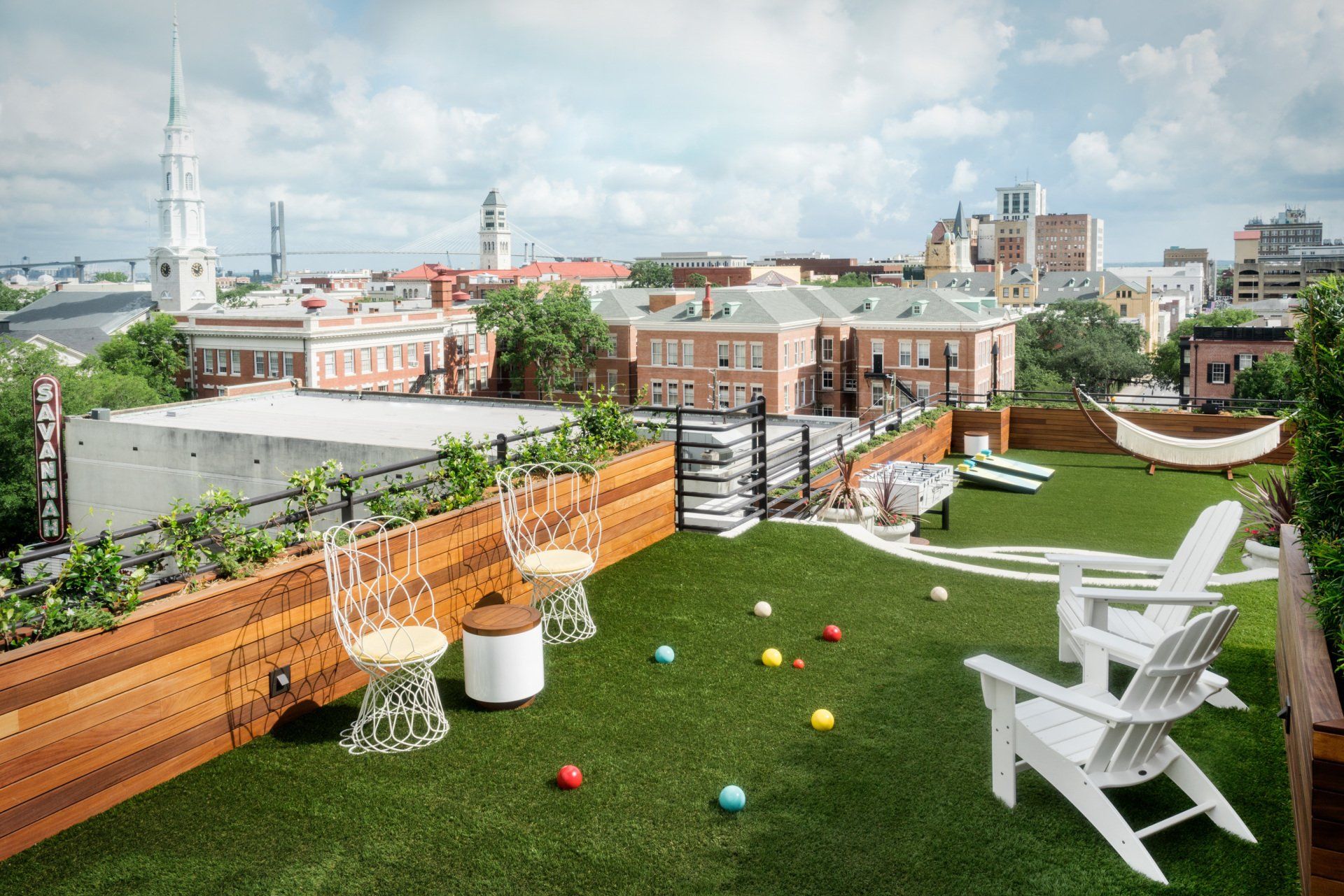 A rooftop garden with chairs , a hammock and balls.