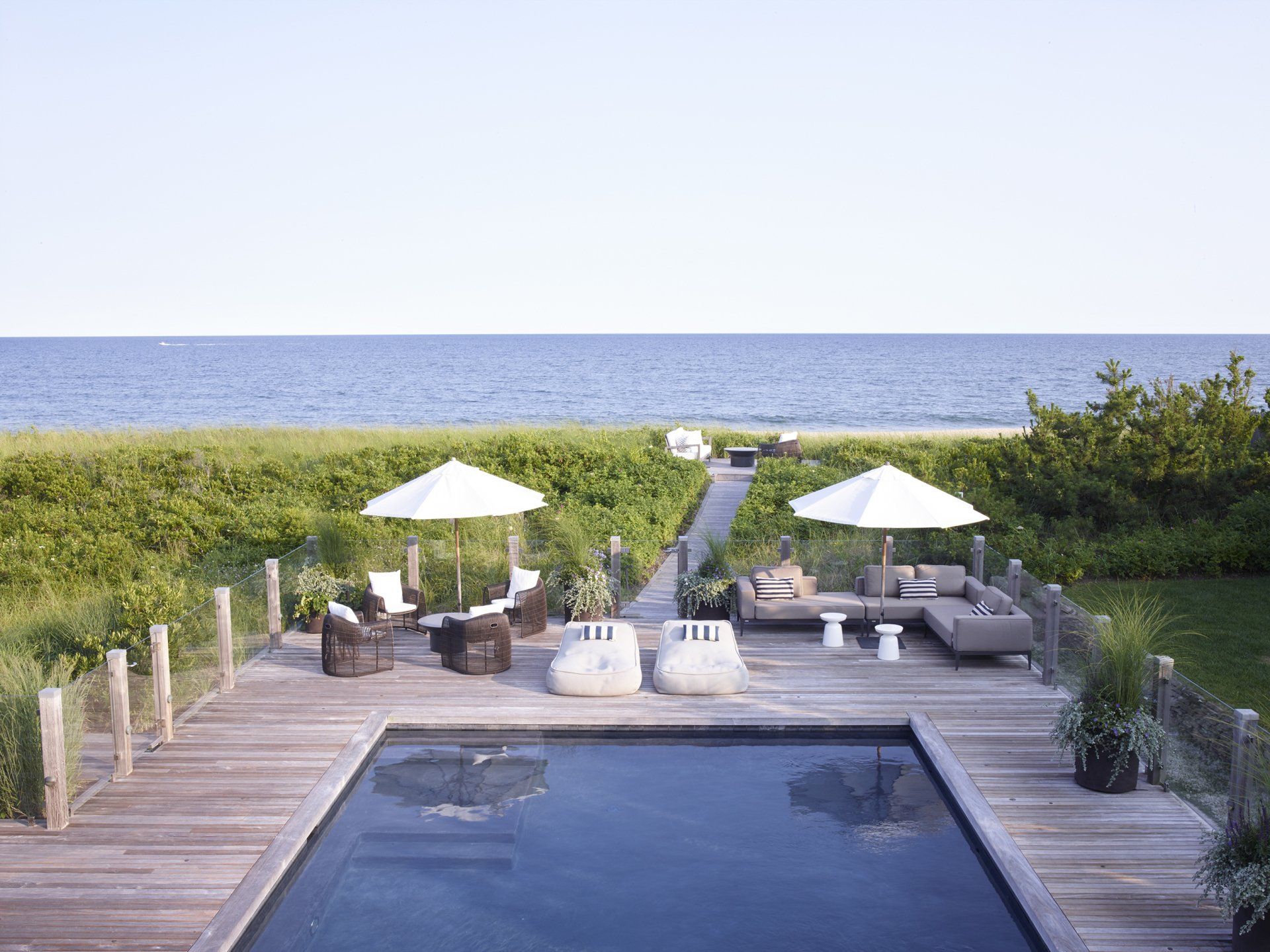 A large swimming pool surrounded by a wooden deck overlooking the ocean